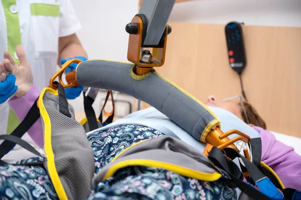 A care staff using a power assist to lifts a patient at nursing home. High quality photo