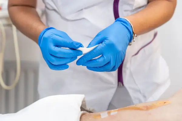 ドクターの手は 男性腹部でクリーンな綿のドレッシング感染創傷を使用しています クリニックでの創傷ドレッシングのための包帯 医療保険のコンセプト 高品質の写真 ストック画像