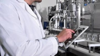 Fabrika işçisi, içecek fabrikasının üretim hattını bilgisayar tabletleriyle inceliyor. Yüksek kalite 4k görüntü