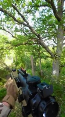 POV Airsoft oyunu. Askeri harekat sırasında ormanda silah taşıyan kamuflaj üniformalı bir asker. Yüksek kalite 4k görüntü