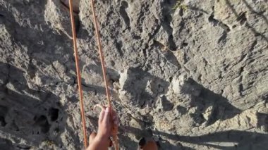 Kaya tırmanışçısının POV 'u uzun bir kaya yüzeyinden aşağı iple iniyor. Yüksek kalite 4k görüntü