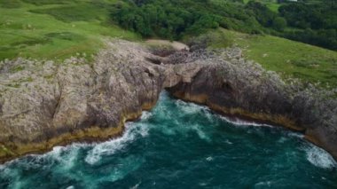 İspanya 'nın Asturias şehrinde kayalık bir kıyı şeridindeki doğal bir kemerin havadan görünüşü. Yüksek kalite 4k görüntü