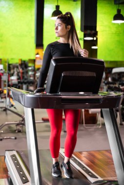 Koşu bandında spor salonunda egzersiz yapan ve antrenman yapan genç bir kadın. Sağlıklı bir yaşam tarzı ve olumlu insanlar. Yüksek kalite fotoğraf