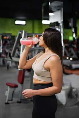 Genç bayan yorucu bir eğitimden sonra rahatlıyor, spordan sonra spor içeceği içen genç bir sporcu. Yüksek kalite fotoğraf