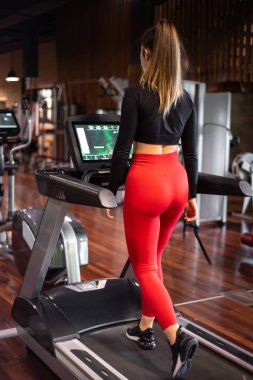 Koşu bandında spor salonunda egzersiz yapan ve antrenman yapan genç bir kadın. Sağlıklı bir yaşam tarzı ve olumlu insanlar. Yüksek kalite fotoğraf