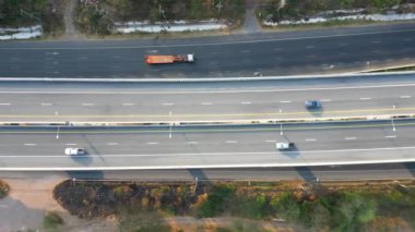 Zıt yönlerde hareket eden arabalar ve kamyonlarla modern yol altyapısını ön plana çıkaran çok şeritli bir otoyolun tepeden aşağı hava görüntüsü.