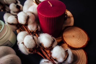 Pamuklu balkabağı ve mumlar, çam kozalağı, siyah kağıt arka planda ahşap duruş