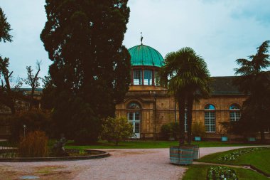 Mavi gökyüzü, yeşil bitkiler ve palmiyelerden oluşan güzel bir bina. Alman şehri Karlsruhe 'nin Botanik Bahçesi