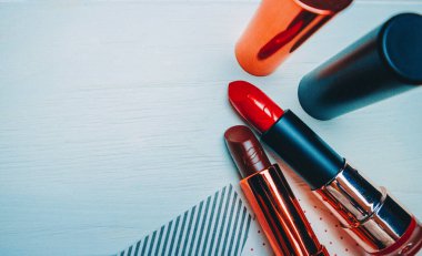 Beyaz ahşap arka planda kırmızı ve kahverengi ruj ve bordo hırka.