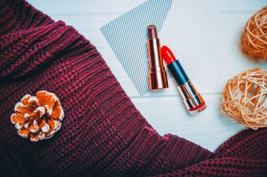 Beyaz ahşap arka planda kırmızı ve kahverengi ruj ve bordo hırka.