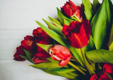 Beyaz ahşap arka planda kırmızı lale buketi.