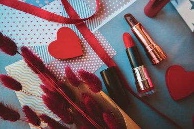 Rujlar, ojeler, langurular ve arka planda kırmızı kalpler. Sevgililer Günü