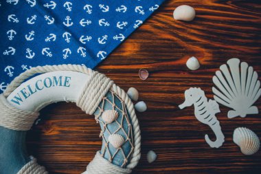 Yaşam şamandırası, denizyıldızı, denizatı, deniz kabuğu, yeşil yapraklar ve ahşap kahverengi arka planda kumaşa sabitlenmiş çapa. Yaz mevsimi