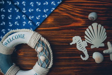 Yaşam şamandırası, denizyıldızı, denizatı, deniz kabuğu, yeşil yapraklar ve ahşap kahverengi arka planda kumaşa sabitlenmiş çapa. Yaz mevsimi