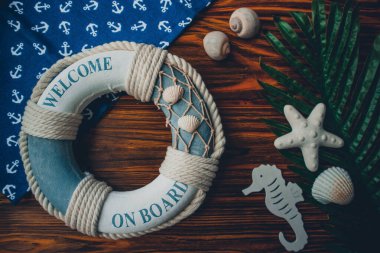 Yaşam şamandırası, denizyıldızı, denizatı, deniz kabuğu, yeşil yapraklar ve ahşap kahverengi arka planda kumaşa sabitlenmiş çapa. Yaz mevsimi