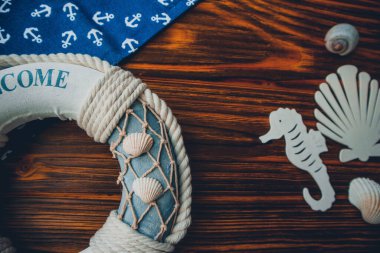 Yaşam şamandırası, denizyıldızı, denizatı, deniz kabuğu, yeşil yapraklar ve ahşap kahverengi arka planda kumaşa sabitlenmiş çapa. Yaz mevsimi