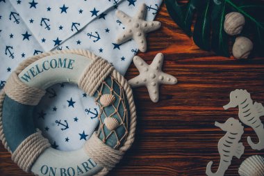 Yaşam şamandırası, denizyıldızı, denizatı, deniz kabuğu, yeşil yapraklar ve ahşap kahverengi arka planda kumaşa sabitlenmiş çapa. Yaz mevsimi