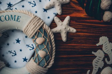 Yaşam şamandırası, denizyıldızı, denizatı, deniz kabuğu, yeşil yapraklar ve ahşap kahverengi arka planda kumaşa sabitlenmiş çapa. Yaz mevsimi