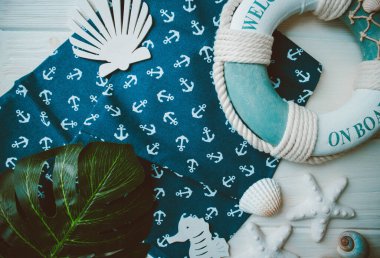 Yaşam şamandırası, denizyıldızı, denizatı, kabuklar, yeşil yapraklar ve ahşap beyaz arka planda kumaşa sabitlenmiş çapa. Yaz mevsimi