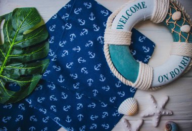 Yaşam şamandırası, denizyıldızı, denizatı, kabuklar, yeşil yapraklar ve ahşap beyaz arka planda kumaşa sabitlenmiş çapa. Yaz mevsimi