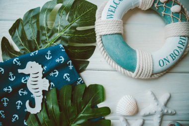 Yaşam şamandırası, denizyıldızı, denizatı, kabuklar, yeşil yapraklar ve ahşap beyaz arka planda kumaşa sabitlenmiş çapa. Yaz mevsimi