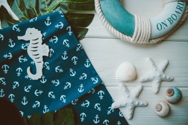 Yaşam şamandırası, denizyıldızı, denizatı, kabuklar, yeşil yapraklar ve ahşap beyaz arka planda kumaşa sabitlenmiş çapa. Yaz mevsimi