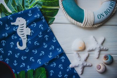 Yaşam şamandırası, denizyıldızı, denizatı, kabuklar, yeşil yapraklar ve ahşap beyaz arka planda kumaşa sabitlenmiş çapa. Yaz mevsimi