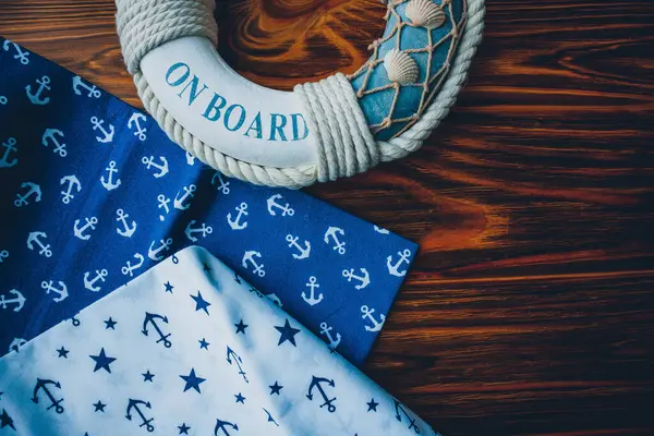 Lifebuoy, denizyıldızı ve ahşap kahverengi arka planda çapa izi kumaşı. Yaz mevsimi