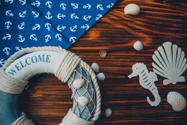 Yaşam şamandırası, denizyıldızı, denizatı, deniz kabuğu, yeşil yapraklar ve ahşap kahverengi arka planda kumaşa sabitlenmiş çapa. Yaz mevsimi