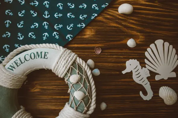 Yaşam şamandırası, denizyıldızı, denizatı, deniz kabuğu, yeşil yapraklar ve ahşap kahverengi arka planda kumaşa sabitlenmiş çapa. Yaz mevsimi