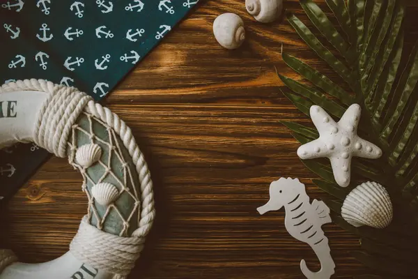 Yaşam şamandırası, denizyıldızı, denizatı, deniz kabuğu, yeşil yapraklar ve ahşap kahverengi arka planda kumaşa sabitlenmiş çapa. Yaz mevsimi