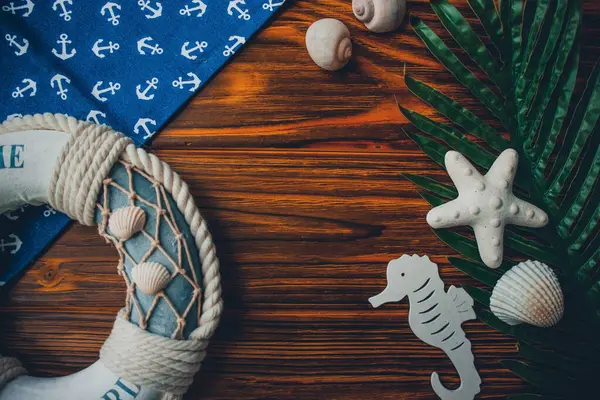 Yaşam şamandırası, denizyıldızı, denizatı, deniz kabuğu, yeşil yapraklar ve ahşap kahverengi arka planda kumaşa sabitlenmiş çapa. Yaz mevsimi