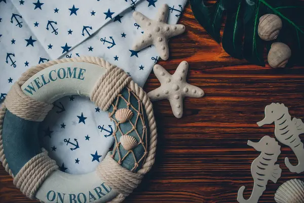 Yaşam şamandırası, denizyıldızı, denizatı, deniz kabuğu, yeşil yapraklar ve ahşap kahverengi arka planda kumaşa sabitlenmiş çapa. Yaz mevsimi