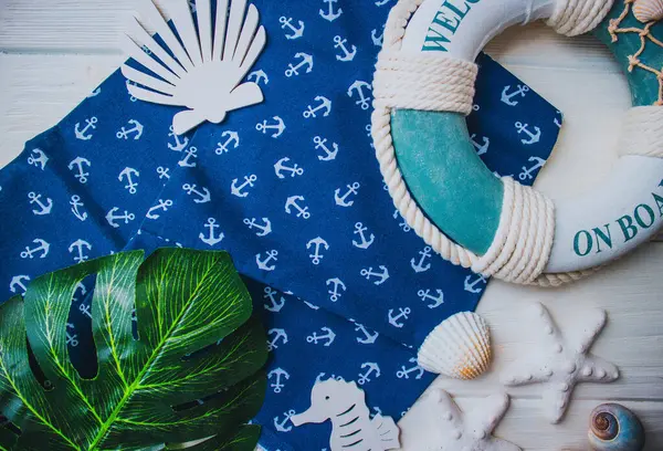 Yaşam şamandırası, denizyıldızı, denizatı, kabuklar, yeşil yapraklar ve ahşap beyaz arka planda kumaşa sabitlenmiş çapa. Yaz mevsimi