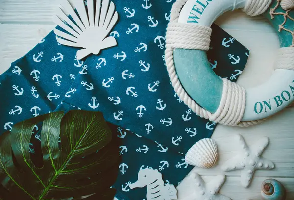 Yaşam şamandırası, denizyıldızı, denizatı, kabuklar, yeşil yapraklar ve ahşap beyaz arka planda kumaşa sabitlenmiş çapa. Yaz mevsimi