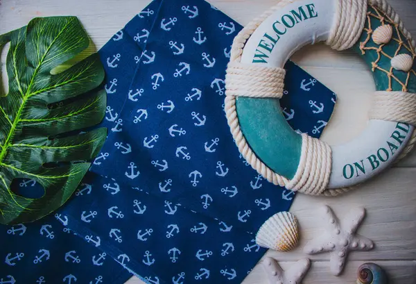 Yaşam şamandırası, denizyıldızı, denizatı, kabuklar, yeşil yapraklar ve ahşap beyaz arka planda kumaşa sabitlenmiş çapa. Yaz mevsimi