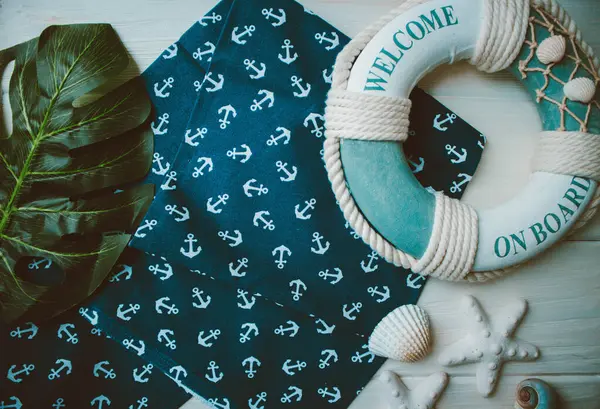 Yaşam şamandırası, denizyıldızı, denizatı, kabuklar, yeşil yapraklar ve ahşap beyaz arka planda kumaşa sabitlenmiş çapa. Yaz mevsimi