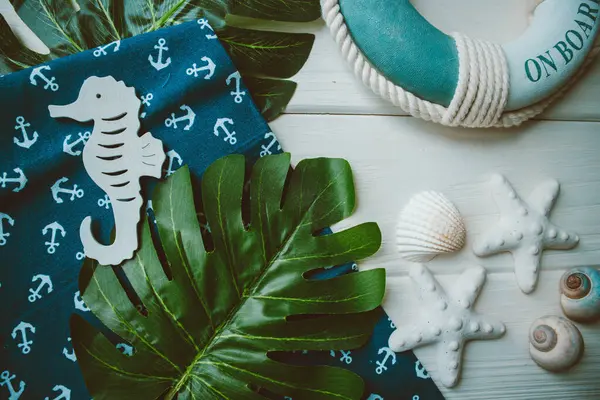 Yaşam şamandırası, denizyıldızı, denizatı, kabuklar, yeşil yapraklar ve ahşap beyaz arka planda kumaşa sabitlenmiş çapa. Yaz mevsimi