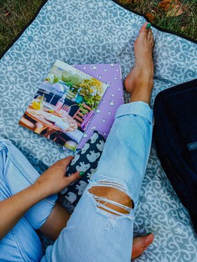 Kadın bacakları, sırt çantası, defter ve dergi. Açık hava eğlencesi