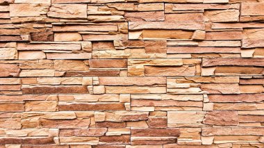 Değişik boyutlarda doğal taş tuğlalardan yapılmış yumuşak bir duvar. Sıcak toprak tonlarında. Kırsal ve davetkar bir görünüm yaratıyor..