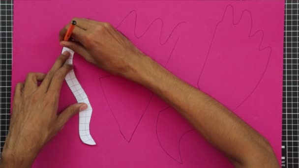 工芸品やプラスチック芸術 ピンクの泡の上にテンプレートをトレースします 切断マット 茶色の手 — ストック動画