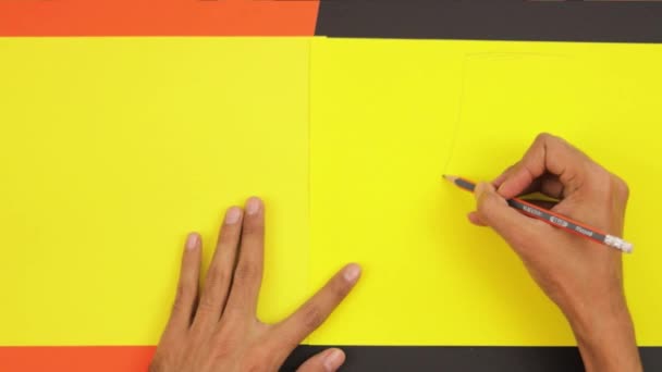 黄色い段ボールに鉛筆で描く 茶色の肌の手 工芸品 プラスチック工芸品 — ストック動画