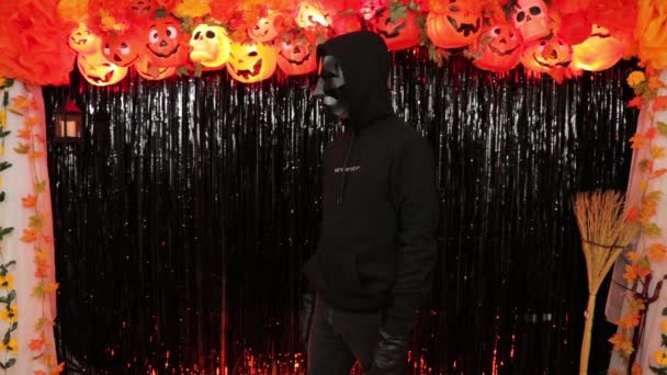 不気味な3D多角形のマスクと黒の衣装の人 ハロウィンのテーマパーティー 秋の装飾 アメリカ軍の銃撃 — ストック動画