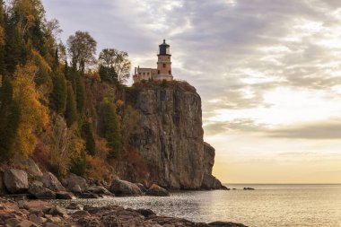 Güz boyunca dramatik bulutlar ve ışıkla gün doğumunda Superior Gölü 'nün kuzey kıyısındaki Split Rock deniz feneri.