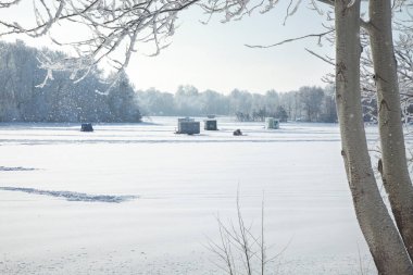 Minnesota gölünde parlak bir kış sabahı buzda balık tutma kulübeleri ve karavanlar.