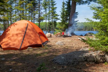 Turuncu çadır ve kamp ateşi Kuzey Minnesota 'nın sınır sularında bir gölde yaz boyunca