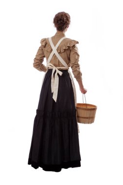 Genç çayır kadını elinde bir sepet tutarak uzaklaşıyor.