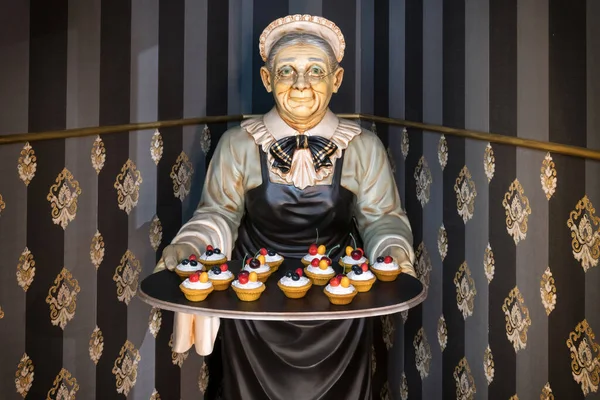 Статуя Бабушки Несущей Поднос Маленькими Пирожными Углу Полосатых Стен Ресторане — стоковое фото