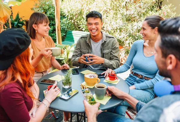 stock image From above group of cheerful multiracial men and women laughing at joke while sitting around table and drinking fresh coffee on summer weekend day in street cafe in park