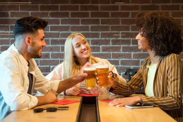 Usmívající Multiraciální Povzbuzování Sklenicemi Studeného Pěnového Piva Zatímco Sedí Stolu — Stock fotografie